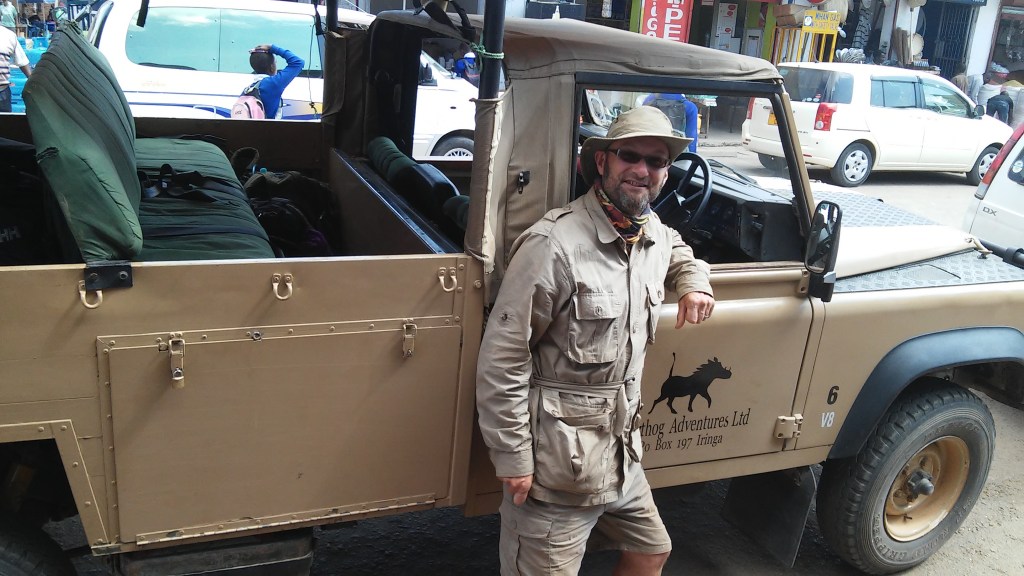 Man in safari gear next to Warthog Adventures Land Rover